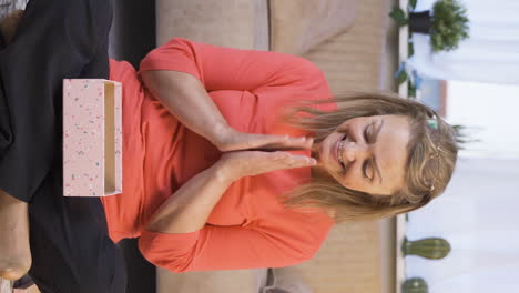 Vertical-video-of-Happy-and-joyful-woman-opening-gift-package.